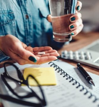 mujer tomando vitaminas mientras estudia